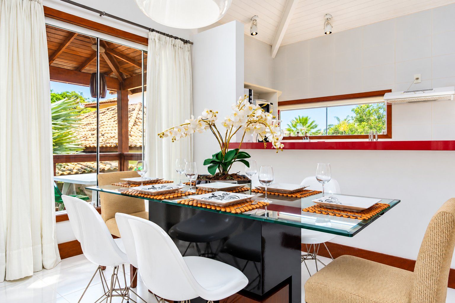 A dining area with a glass table, white chairs, and a view of the outdoors.