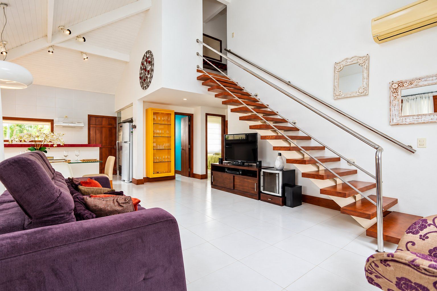 A spacious living area with a modern staircase, a dining area, and a kitchen.