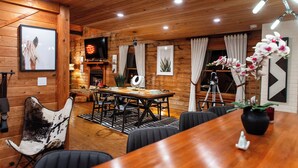 A wooden interior with a dining table, chairs, a TV, and a tripod. - Peaceful Farm Cabin Getaway, 2BR w/ WiFi, AC & Sunrise Views (Okeechobee)