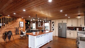 A spacious kitchen with wooden floors, a central island, and modern appliances. - Peaceful Farm Cabin Getaway, 2BR w/ WiFi, AC & Sunrise Views (Okeechobee)
