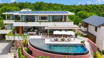 Una casa moderna de dos pisos con piscina y paneles solares.