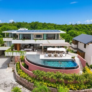 Une maison moderne à deux étages, dotée d’une piscine et de panneaux solaires.