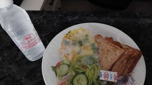 Ein Teller mit Salat, Gurkenscheiben und einem Päckchen Salz.