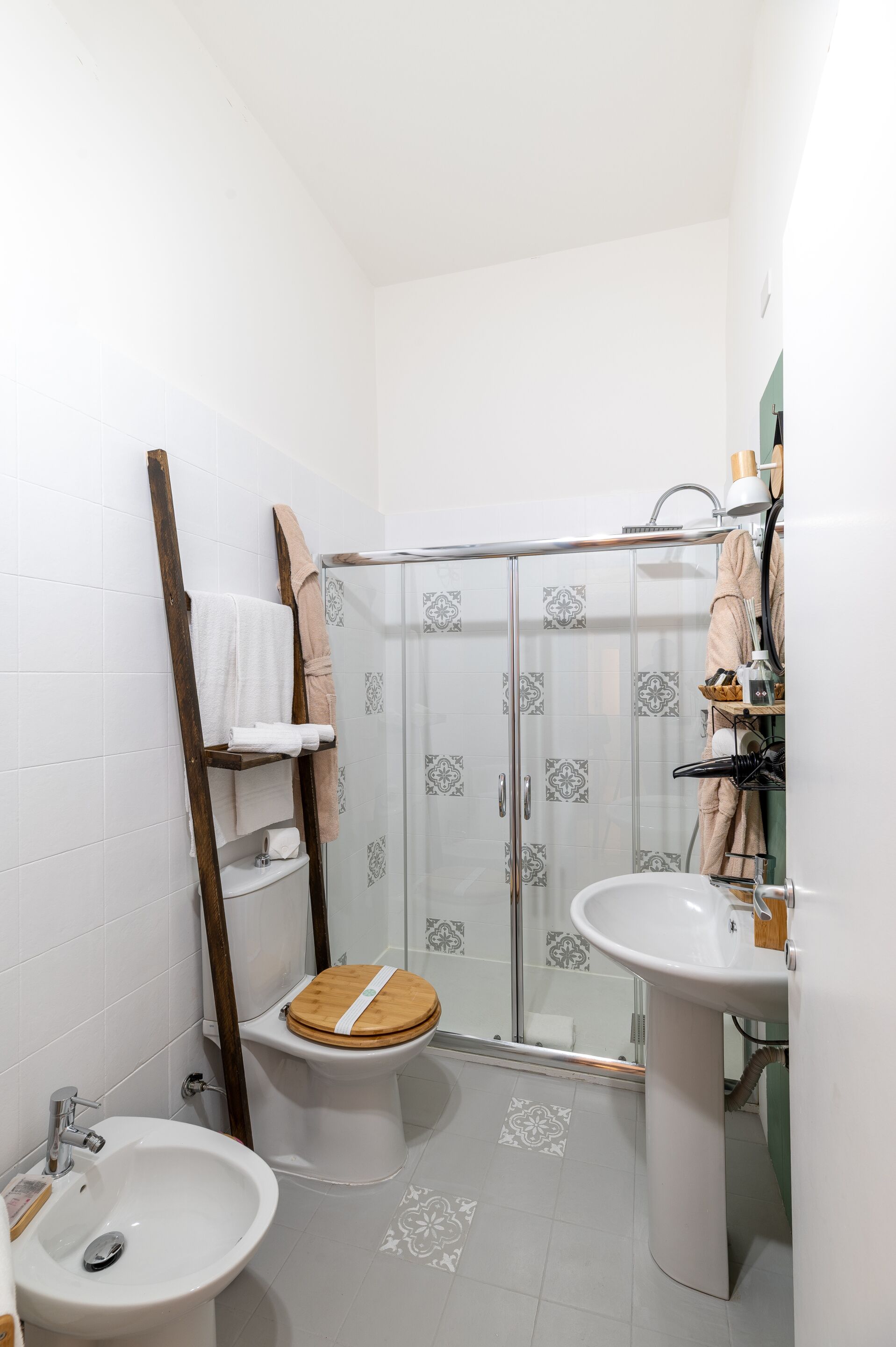 A compact bathroom with a shower, toilet, bidet, and sink.