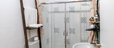 A compact bathroom with a shower, toilet, bidet, and sink.
