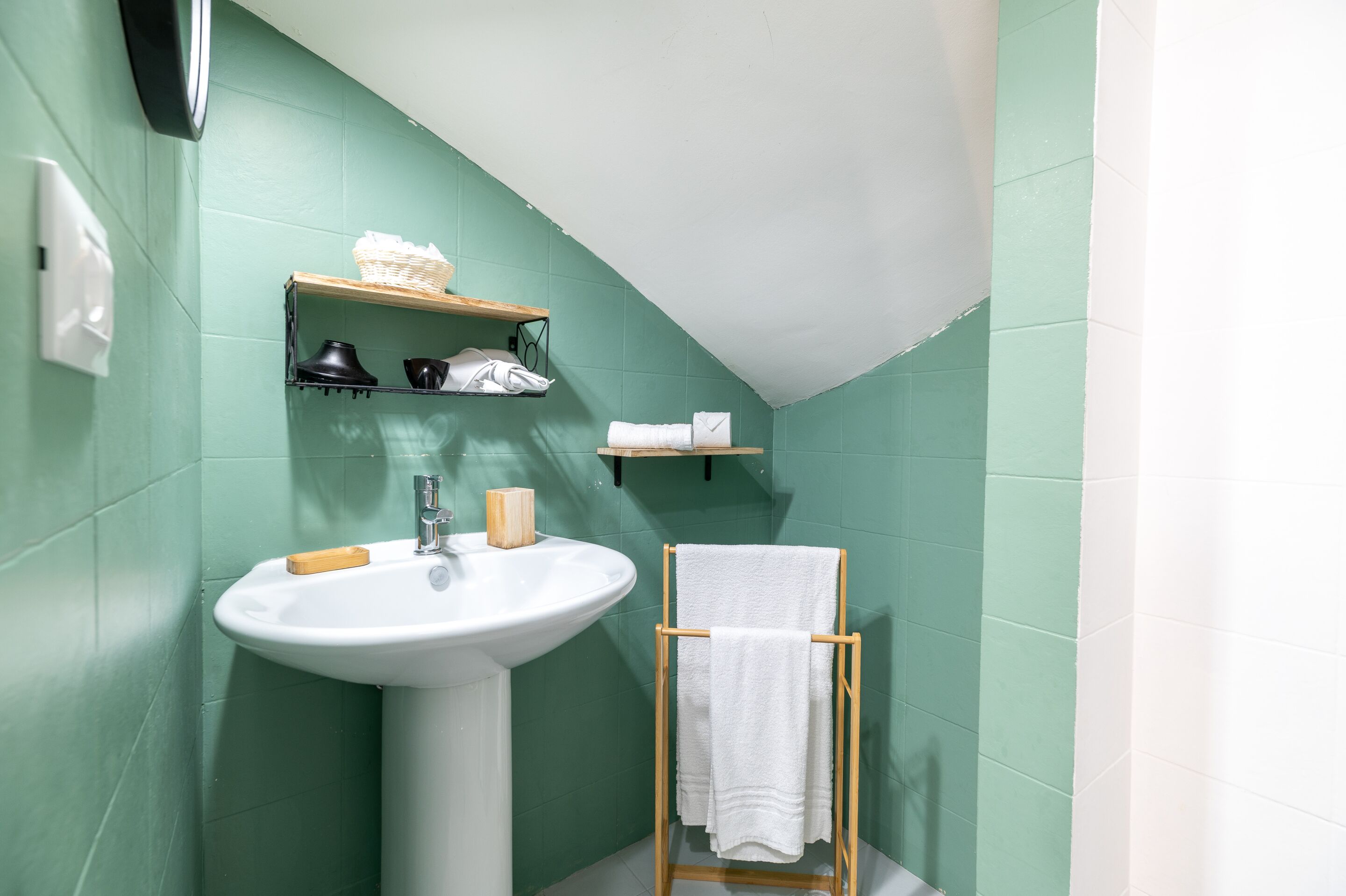 Een badkamer met een wastafel, planken met toiletartikelen en een handdoekhouder.