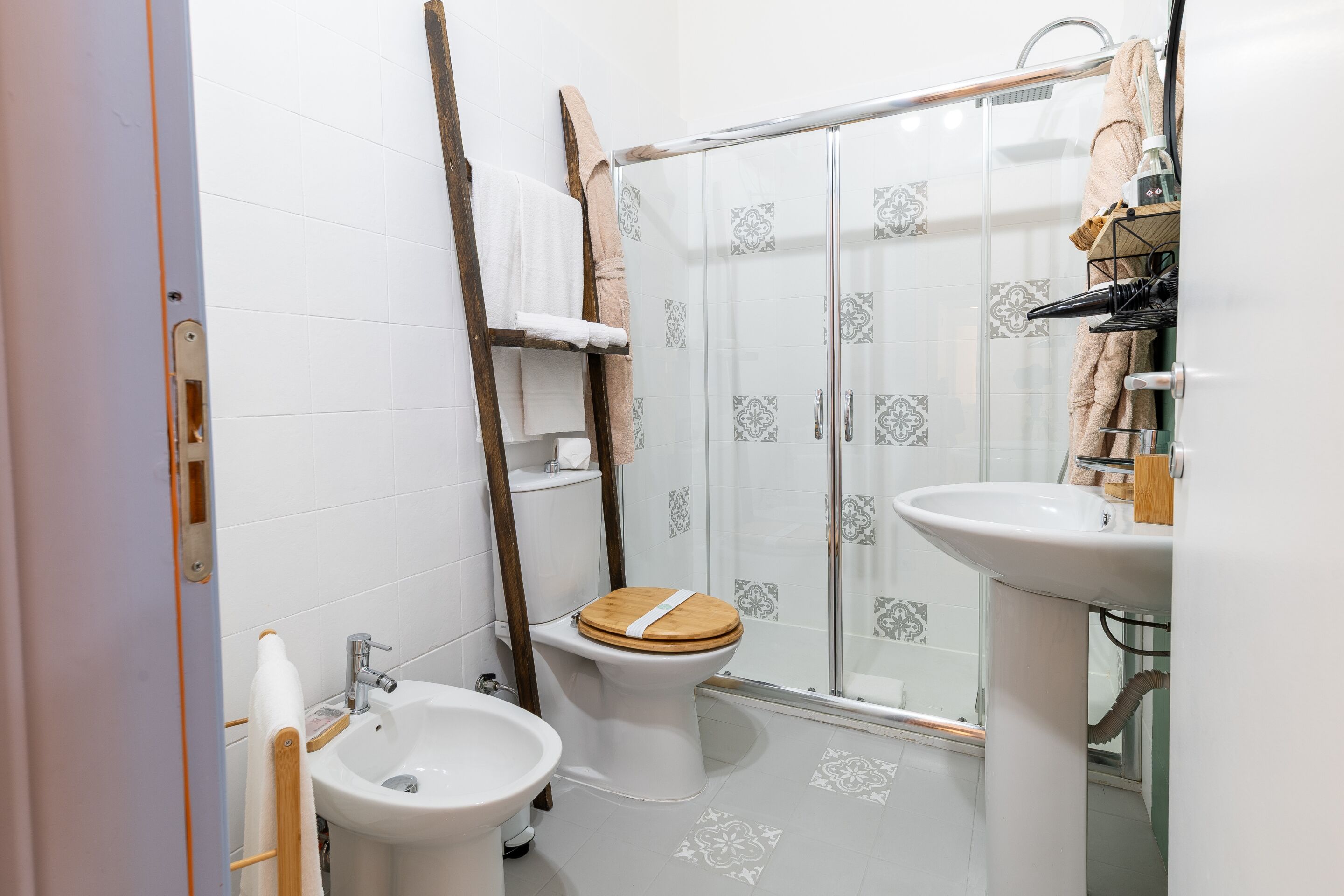 Une salle de bain comprenant des toilettes, un bidet, un lavabo et une douche à parois en verre.