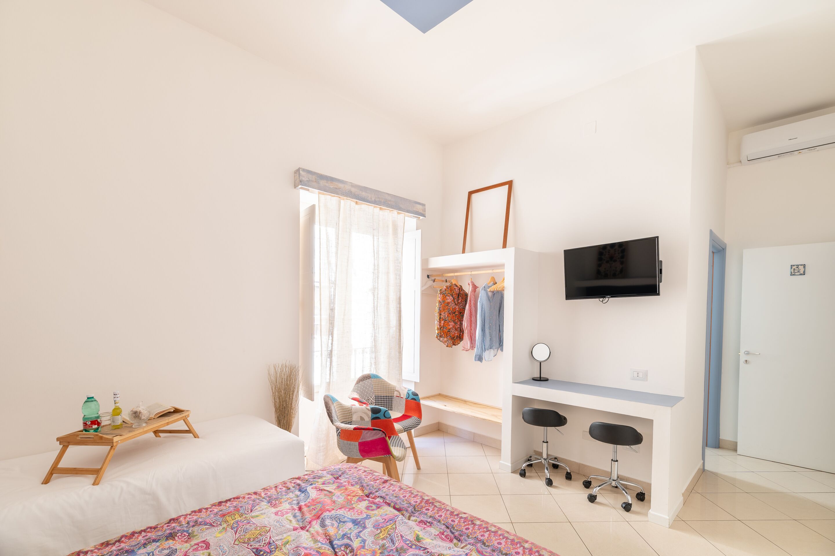 Een slaapkamer met een bed, een bureau, een stoel, een televisie en een kledingkast.