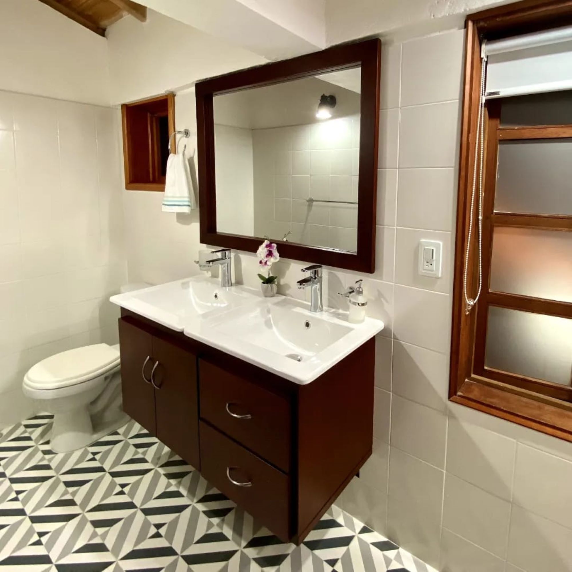 Un baño con tocador de doble lavamanos, inodoro y espejo.
