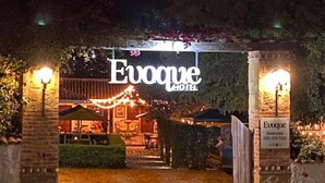 The entrance to the Evogue Hotel with a sign above the door and a pathway leading to the entrance.
