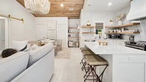 A modern kitchen with white cabinetry, a central island, and bar stools.