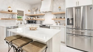 A modern kitchen with a central island, stainless steel appliances, and wooden accents.