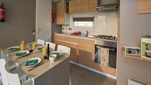 Une cuisine de taille réduite, dotée de meubles en bois, d’une cuisinière à gaz et d’un four encastré.