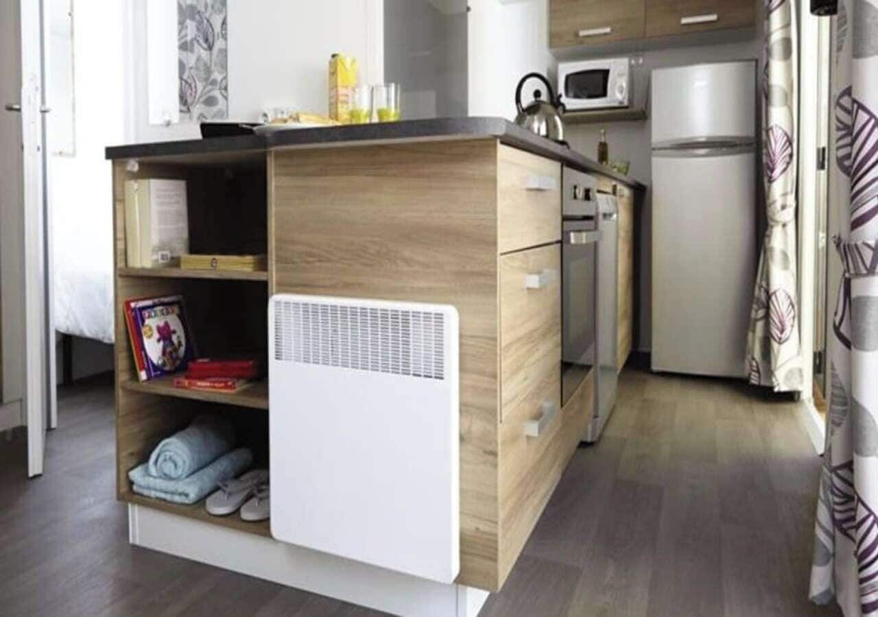 A compact kitchen with a built-in microwave, a small refrigerator, and a white air purifier.