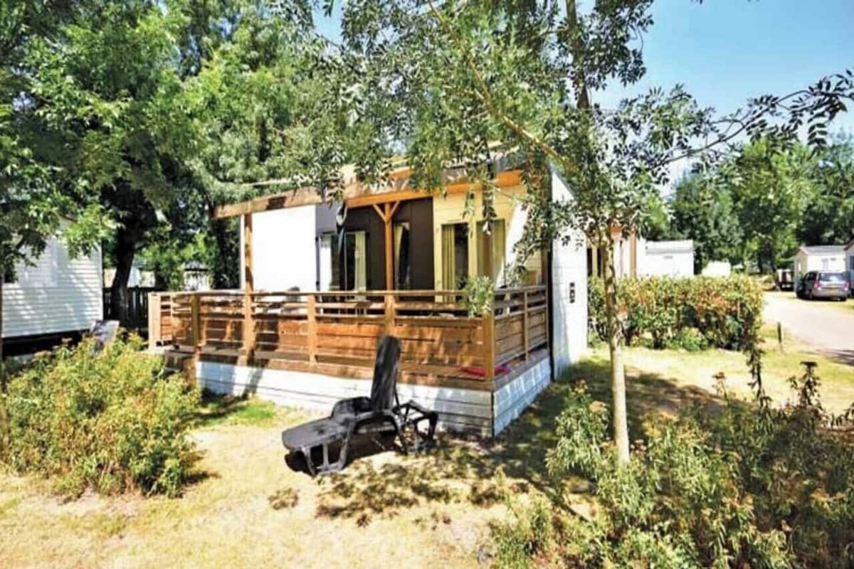 Une petite cabane en bois avec une véranda, une seule chaise et une petite table.