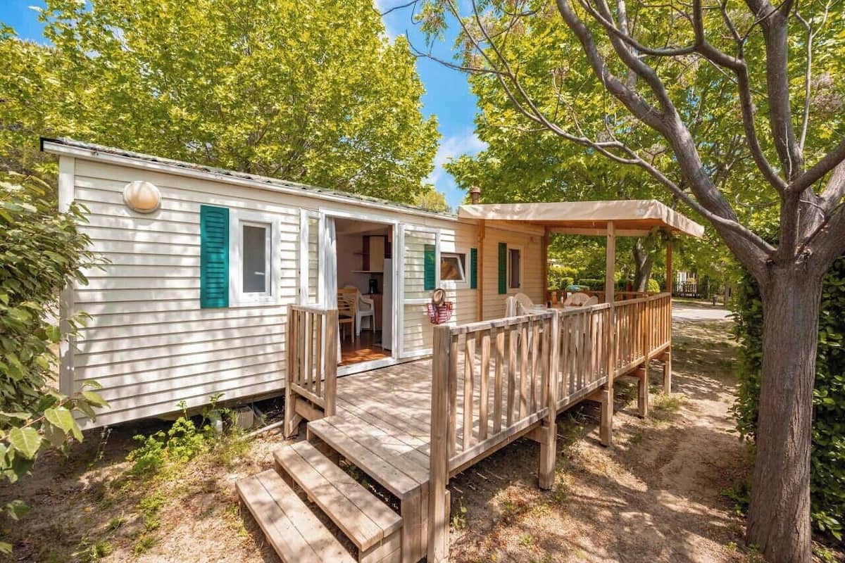 Une maison mobile dotée d’une terrasse en bois et d’un porche couvert.