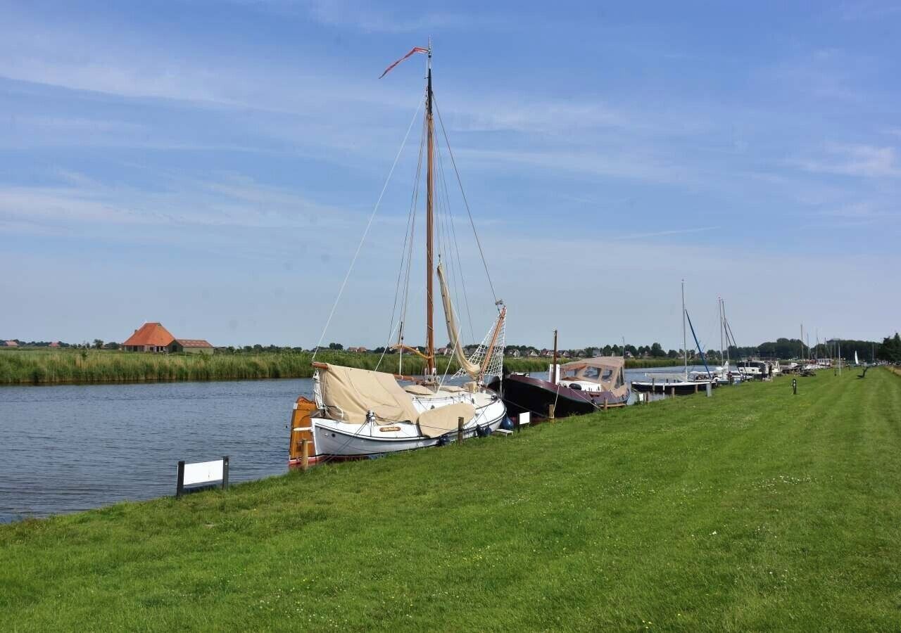 A grassy waterfront area with several boats docked along the shore.