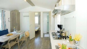 Une cuisine compacte comprenant un coin repas, une cuisinière visible et une petite table à manger avec des chaises.
