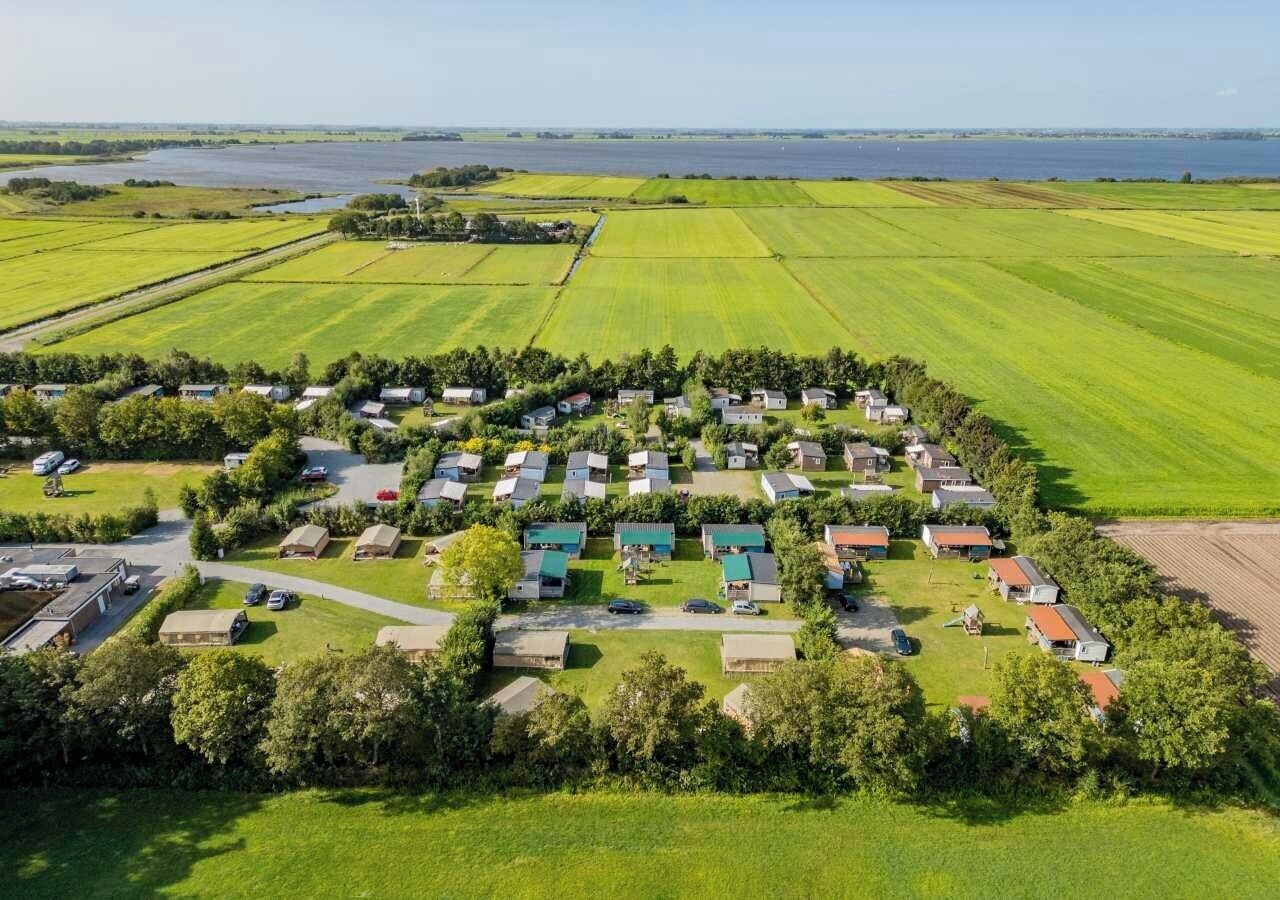 En vy från ovan över en campingplats med flera stugor, en parkeringsplats och grönområden runt omkring.