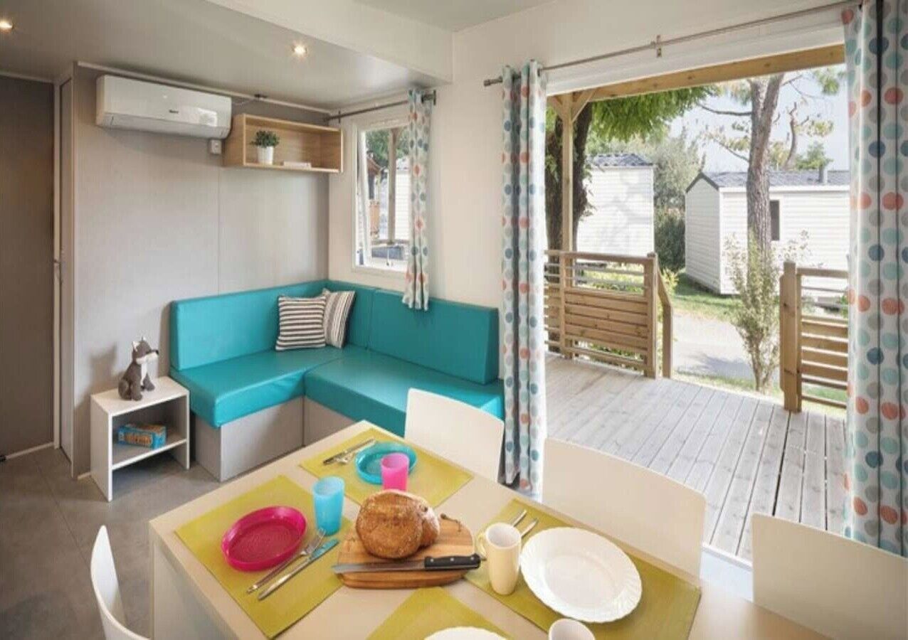 A cozy room with a teal sofa, a dining table with a meal, and a view of the outside.