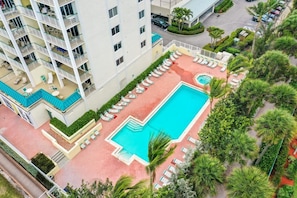 A multi-story hotel with a rooftop pool area, including lounge chairs and a swimming pool. - Beachfront Condo With Restaurant, Pool, spa and gym (Marco Island)