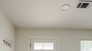 A hallway with a white door, a white couch, and a textured rug. - Spacious 4BR Home, Central Georgetown Location! (Georgetown)