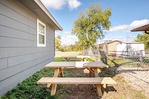 A wooden picnic table set up in a backyard with a house in the background.