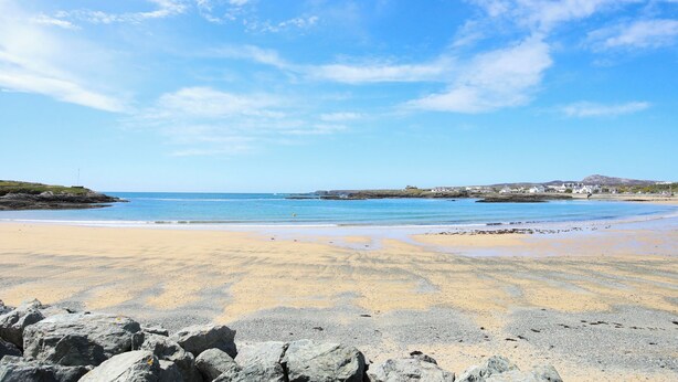 A beach with a clear sky, rocky foreground, and distant buildings. - Beach Court Hideaway (Holyhead)