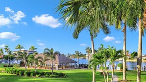 Ein Resort mit Pool, Palmen und einem strohgedeckten Gebäude.