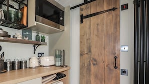 Eine Küche mit Holztür, Mikrowelle, Toaster und Kühlschrank.