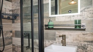 Ein modernes Badezimmer mit einer Duschkabine aus Glas, einem weißen Waschbecken und einem Spiegel darüber.