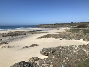 Een rotsachtig strand met een helder uitzicht op de oceaan en verre huizen.
