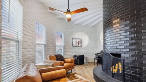 Una sala de estar con chimenea, sofás de cuero y un ventilador de techo.