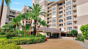 A multi-story hotel with a central courtyard, palm trees, and a covered entrance. - Somerset Three-bedroom end Unit Beachfront Condo (Marco Island)
