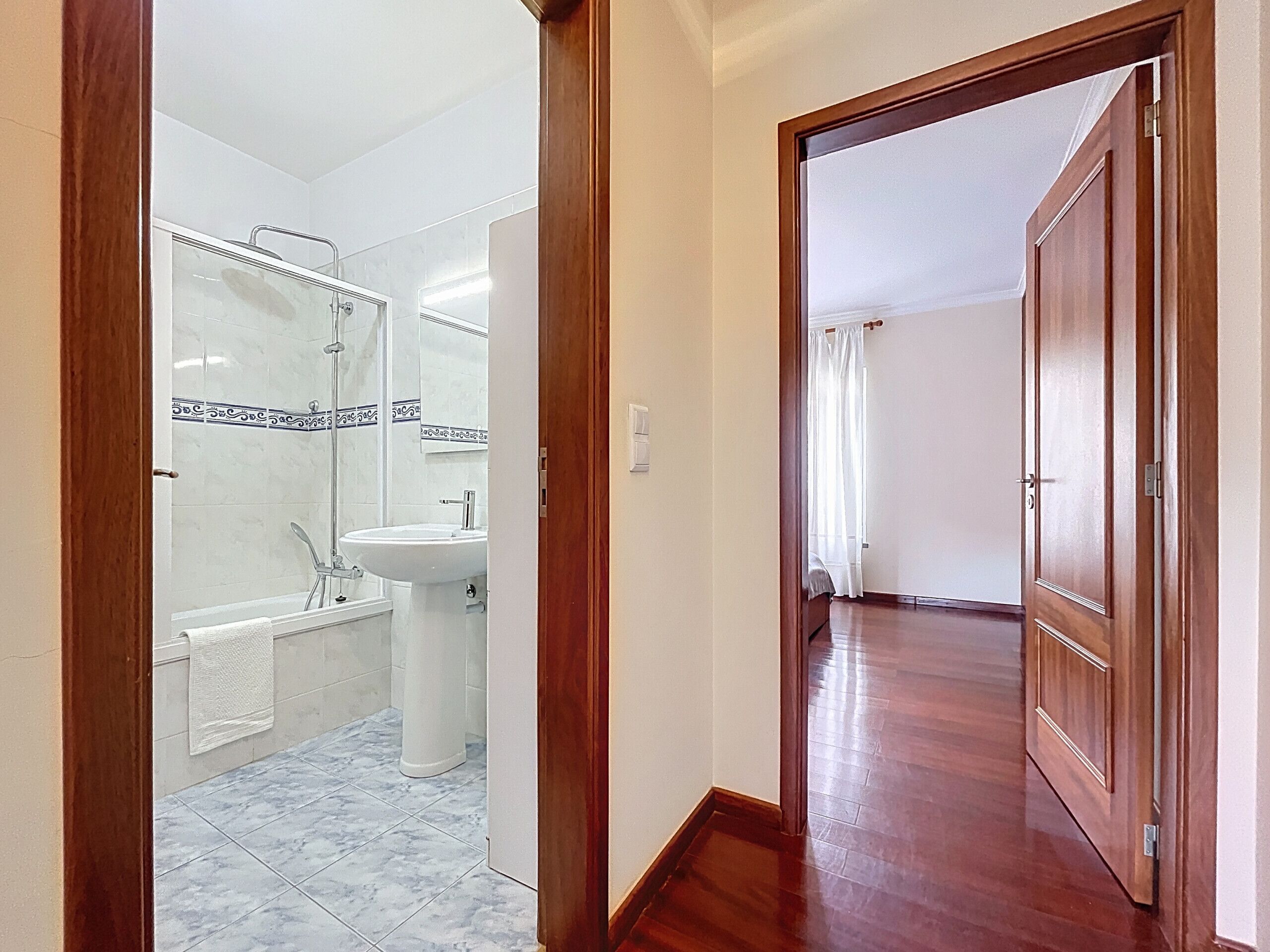 A bathroom with a sink, mirror, and shower.