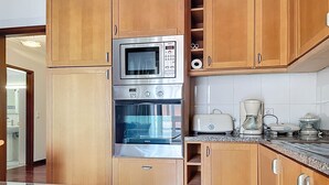 Una cocina con armarios de madera, un microondas Bosch, un horno y una cafetera.