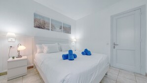 A hotel room with a bed, two bedside tables with lamps, a door, and three wall-mounted pictures. - Eva Vacation Home Pool & Relax - Very close to the beach (Puerto del Carmen)