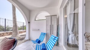 A balcony with two striped lounge chairs, a glass door, and a view of the landscape. - Eva Vacation Home Pool & Relax - Very close to the beach (Puerto del Carmen)