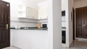 Una cocina con armarios blancos, encimera de granito y microondas.