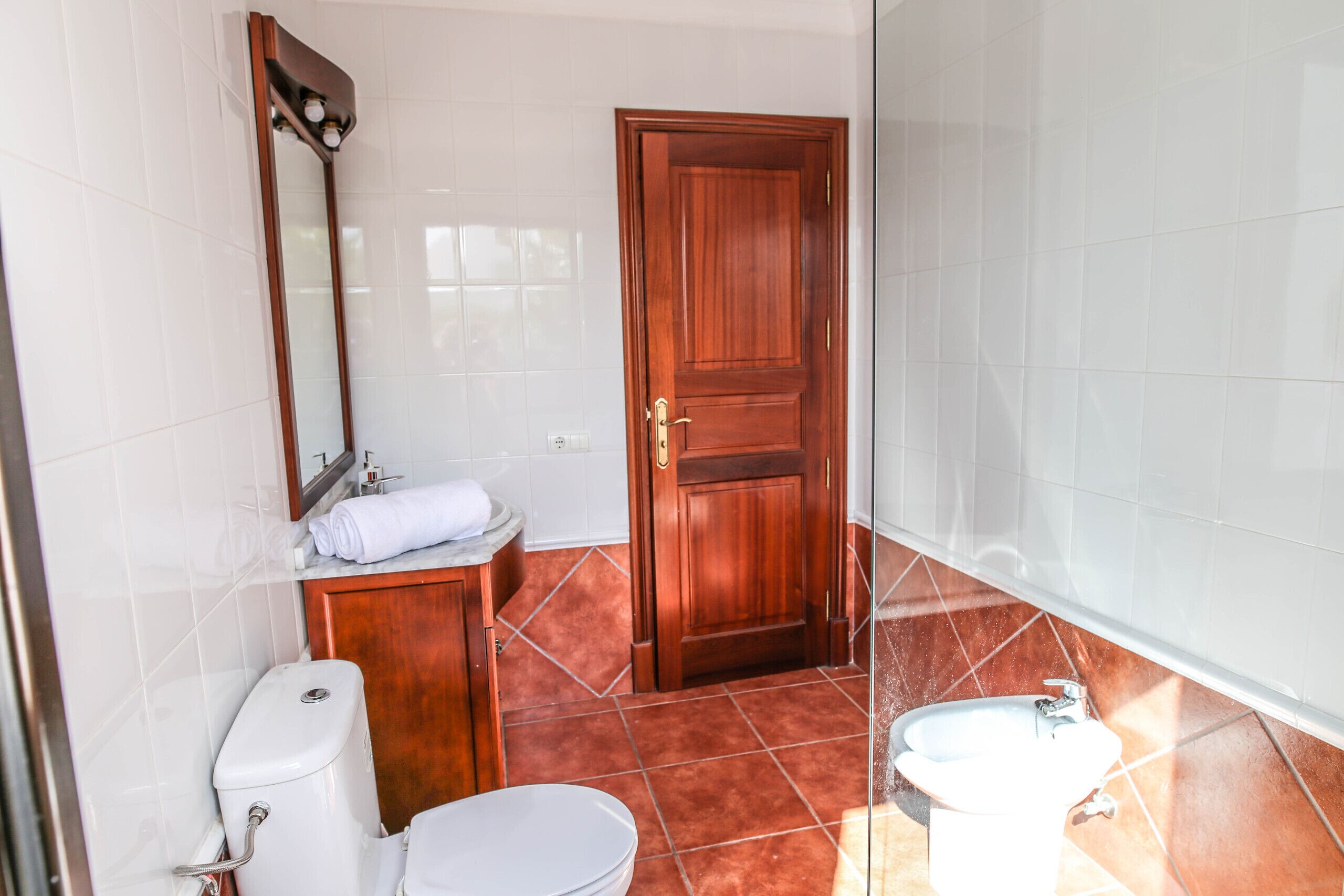 Une salle de bain avec des toilettes, un lavabo et une porte en bois.