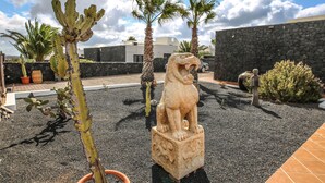 A courtyard with a cactus, palm trees, and a stone lion statue. - Horizon Luxury -A peaceful oasis with private pool (Macher)