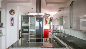A modern kitchen with stainless steel appliances, a granite countertop, and a central range hood. - Horizon Luxury -A peaceful oasis with private pool (Macher)