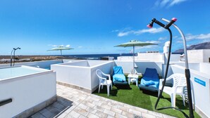 A rooftop terrace with a pool, lounge chairs, and umbrellas.
