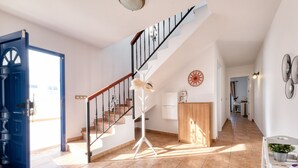 Een ruim interieur met een trap, een blauwe deur en een gang naar een andere kamer.