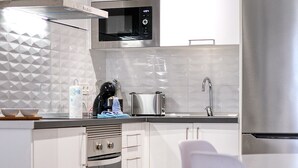 Uma cozinha moderna com armários brancos, micro-ondas, torradeira e geladeira de aço inoxidável.