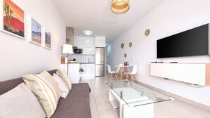 Ein modernes Wohnzimmer mit einer Couch, einem Glastisch und einem flachbildfernseher an der Wand.