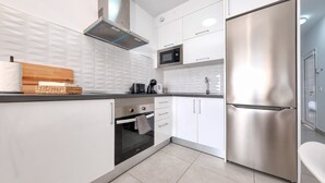 Eine moderne Küche mit weißen Schränken, einem Edelstahl-Kühlschrank, einer Mikrowelle und einem eingebauten Backofen.