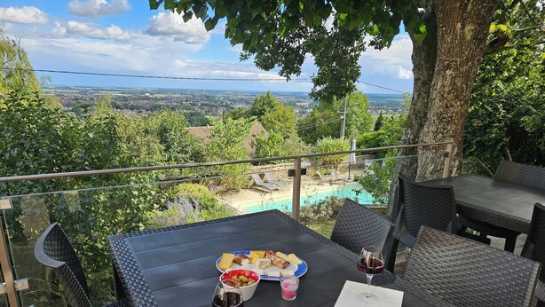 Mesa posta ao ar livre, com vista para uma piscina e paisagem.