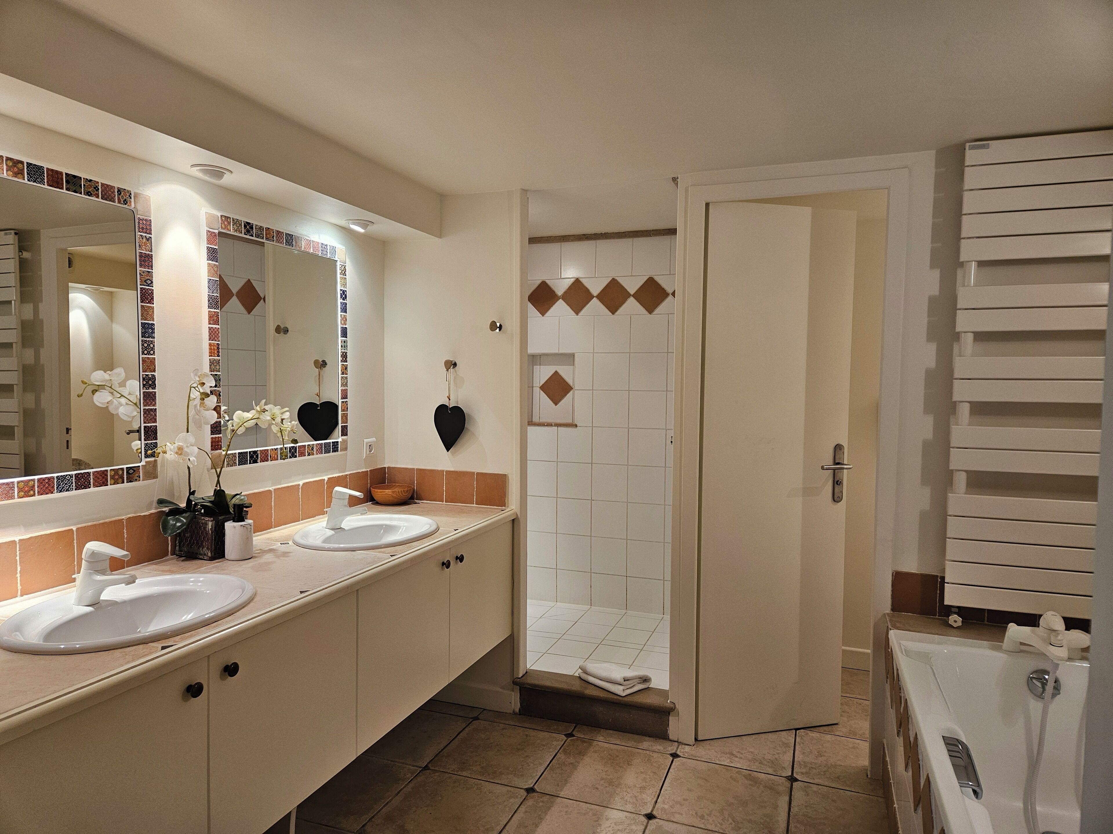 A modern bathroom with two sinks, a large mirror, and a shower area.