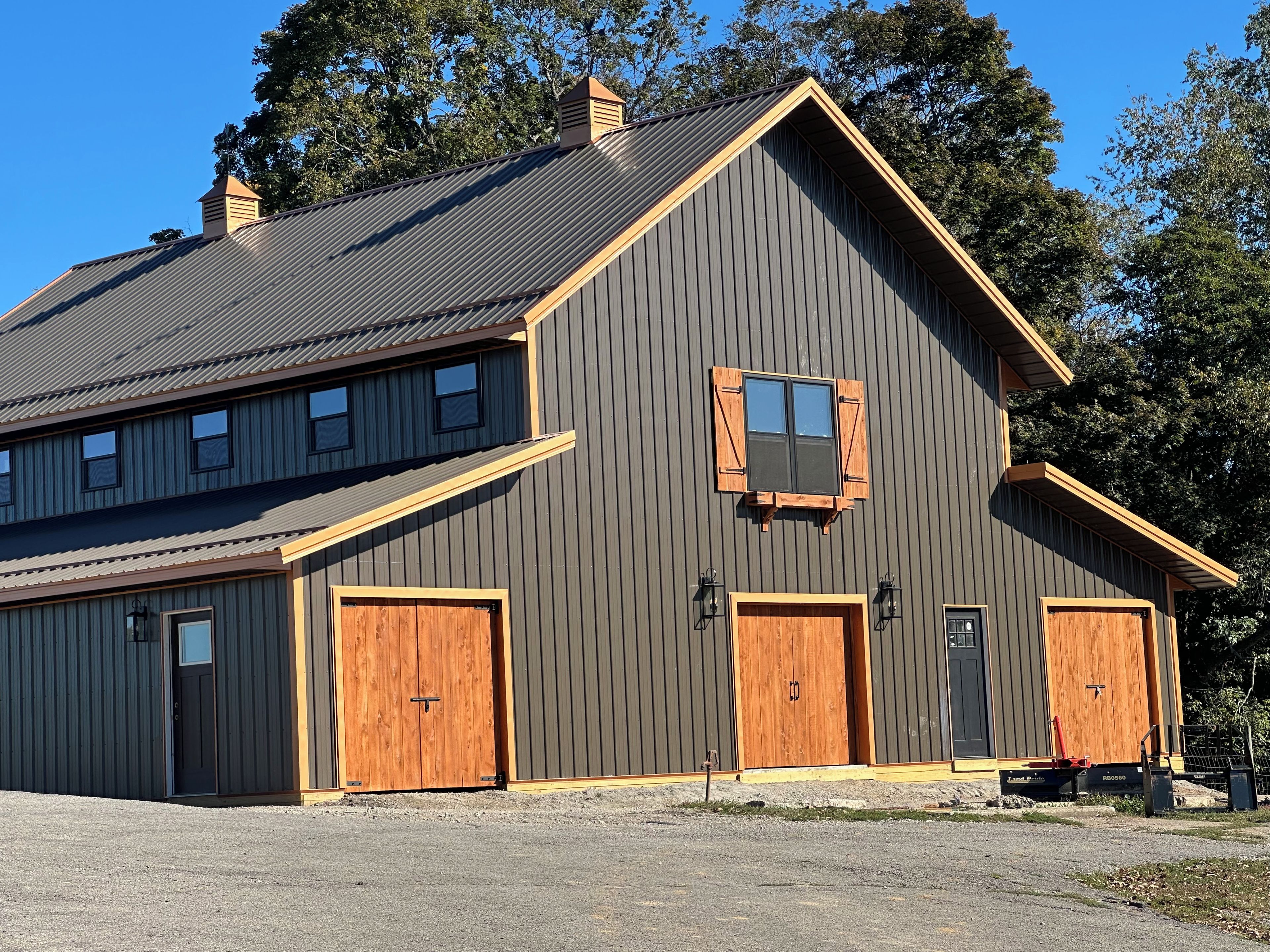 A two-story building with a gabled roof, large wooden doors, and a small window with shutters.